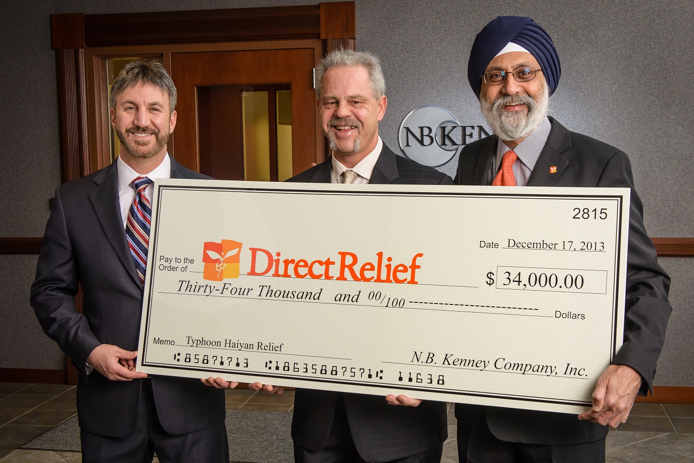NB Kenney President Steven Kenney (L) and Executive Vice President Robert Nims (Center) present a $34,000 donation to Bhupi Singh (R), CFO/COO of Direct Relief