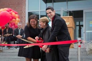 Grad student Lauren Ghazal, Regis President Toni Hays, and undergraduate Student Government President Matt Norton actually cut the ribbon, laughing at the oversize scissors. Vinicius Gorgati, principal of Sasaki Associates, the architectural design firm that redesigned our inner campus, is smiling in the background.