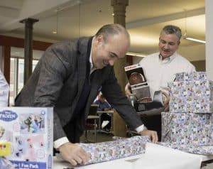 Shawmut executives Les Hiscoe, and Kevin Sullivan wrap gifts for The Home for Little Wanderers in Boston as part of Shawmut’s Project Happier Holidays initiative.